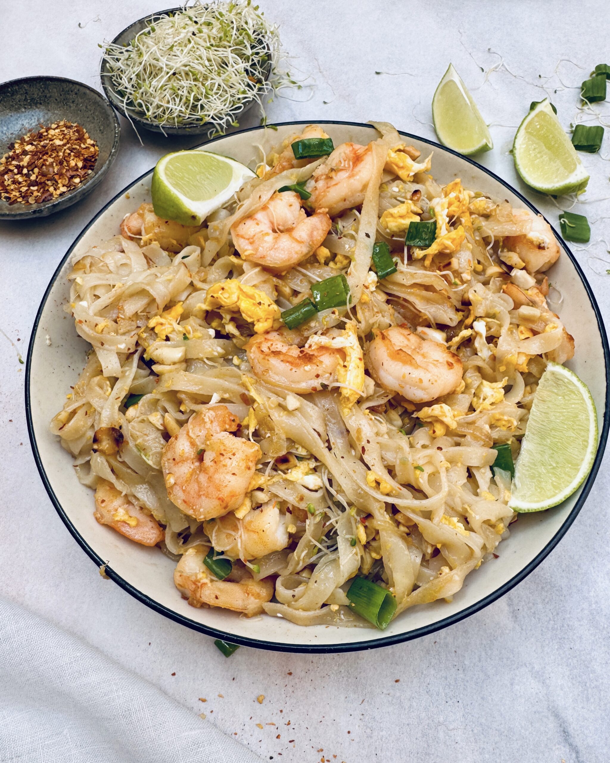 a plate with pad thai, rice noodles with prawns, egg, lime and pad thai sauce